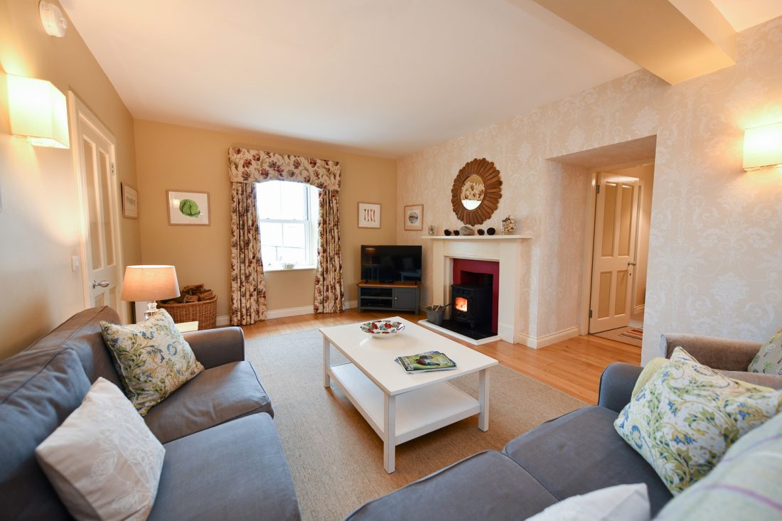 Sitting room with log burning stove, a coffee table and corner sofa