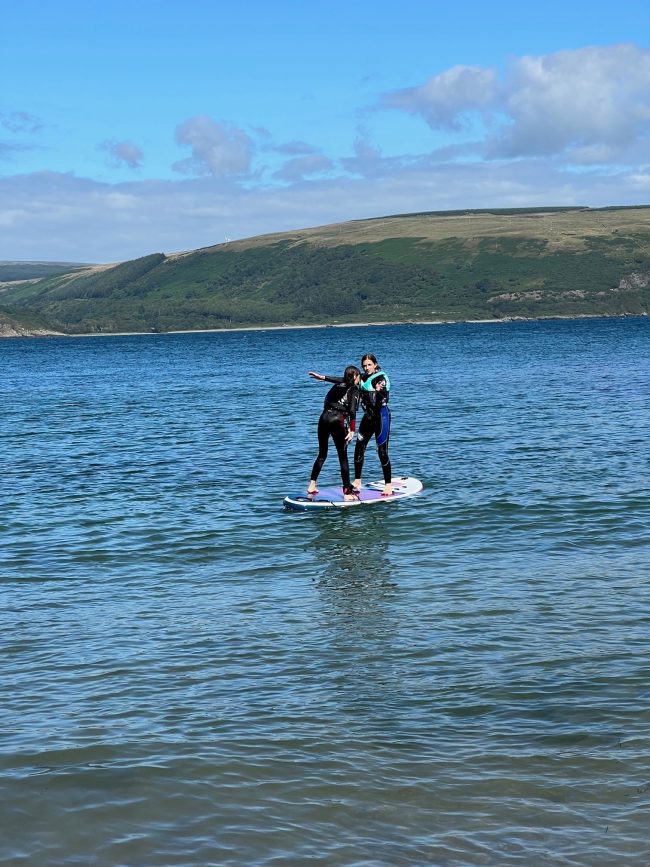 Two people on a paddle board on the sea near our luxury holiday cottages by the coast in Dumfries and Galloway